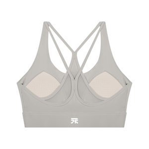 Back of the light gray sports bra, the straps crossing over a mesh panel above the logo on the band