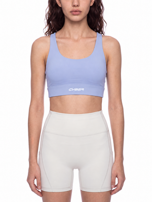 A model wears the lavender sports bra with cream shorts, front view, the band sitting above the waist