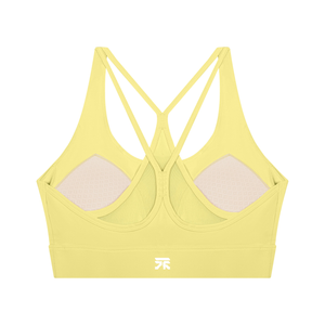 Back of the yellow sports bra laid flat, strappy cross back over mesh with the padded cups showing