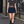 Model walking down a street in the Navy Blue pleated tennis skirt with a grey crop tee and black boots