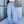 Woman wearing the blue Striped Wide Leg Y2K Pants with a white crop top, front view on a city street