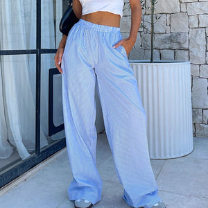Woman wearing the blue Striped Wide Leg Y2K Pants with a white crop top, front view on a city street