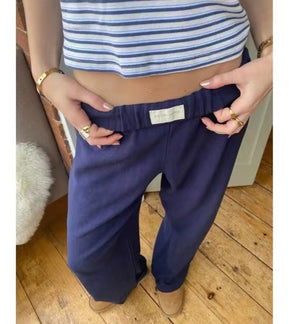 Navy blue elastic waist pants held at the waistband, close view of the plain label and soft fabric