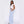 Sky blue pinstripe wide leg pants, full side view of a woman with a white crop top and shoulder bag