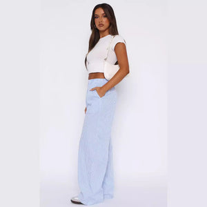 Sky blue pinstripe wide leg pants, full side view of a woman with a white crop top and shoulder bag
