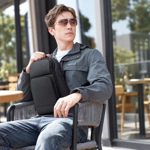 Tablet Sling Techwear Bag worn by a man in a grey jacket, front view seated and back view standing