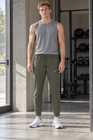 Man in Gray Green Tapered Drawstring Gym Sweatpants and a gray tank top, front view inside a gym