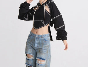 Person wearing a black cut-out jacket and ripped jeans on a white background