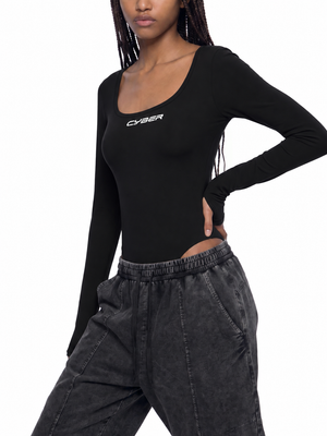 Model with a hand on her hip in the black scoop neck bodysuit and washed black pants, three quarter view