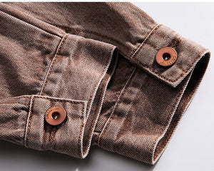 Nærbillede af den falmede brune denimmanchet med to kobberfarvede knapper og mørkere skygge i sømmene