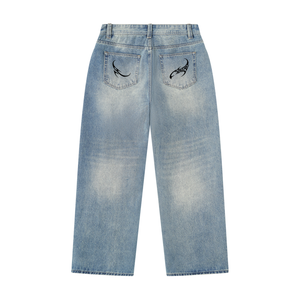 Back of the vintage wash baggy jeans laid flat, black tribal emblems on both back pockets and a faded seat
