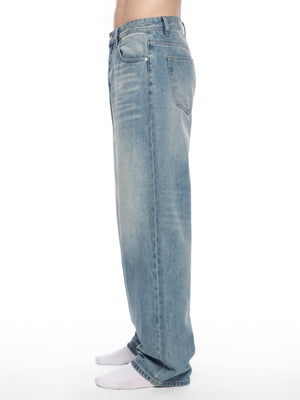 Side view of the vintage wash jeans on a model, the wide leg falling straight to white socks