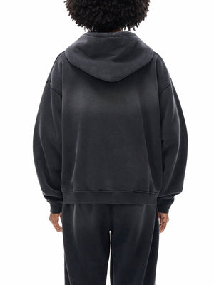 Back view of the black hoodie on the model, worn with matching washed trousers