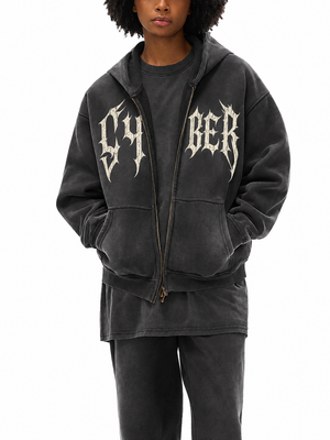 A model stands with hands in the pockets, the zip pulled halfway up the printed chest