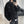 Black washed denim trucker jacket in a mirror selfie, front view with a hand in the pocket