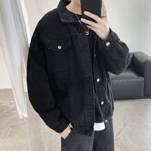 Black washed denim trucker jacket in a mirror selfie, front view with a hand in the pocket