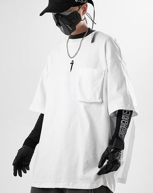 Person wearing a white oversized shirt with black text, black gloves, and a black cap on a white background