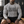 A tattooed man sits on a bench in the flecking gray compression shirt and black shorts, front view