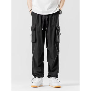 Black colourway front view, loose wide legs, large flap pockets and drawcord toggles at the ankles