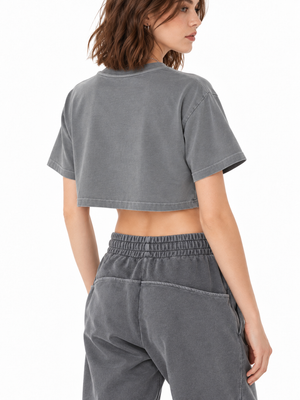 Back view of the grey washed crop top on a model, plain back, dropped shoulders and a short cropped hem