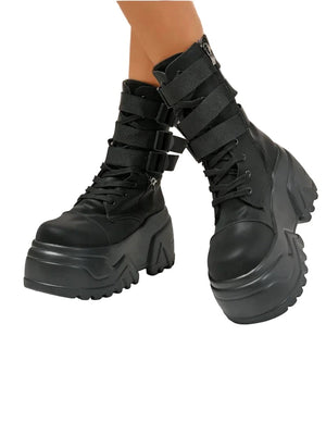 Black platform boots with multiple straps on a neutral background