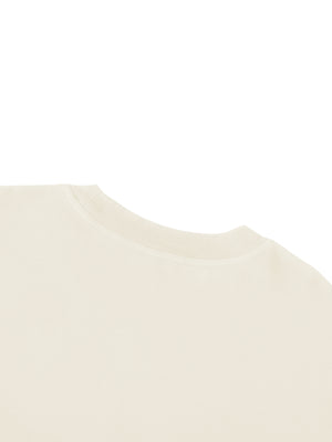 Shoulder and neckline of the apricot tee, the drop shoulder seam falling below the natural line