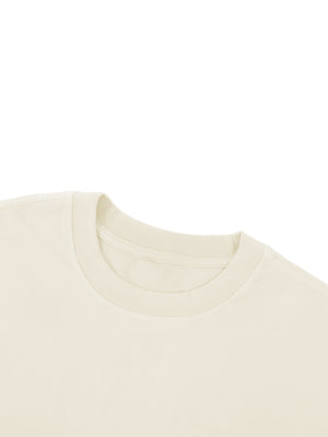 Close-up of the ribbed crew collar on the apricot tee, stitched flat where it meets the shoulder