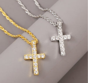 Y2K ketting met iced kruis in goudkleurig en zilverkleurig, twee koordkettingen met kruishangers met stenen op een grijs oppervlak