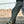 Green cyberpunk pants on a man leaning on a car, side view of the zipped thigh pocket and knee panel seams