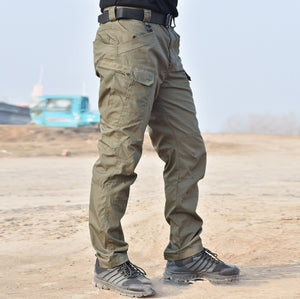 Green tactical pants in three-quarter front view outdoors, large thigh cargo pocket and straight leg to the ankle