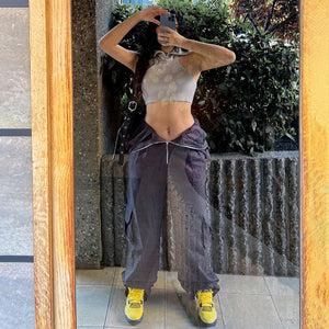 Front view of the charcoal cargo pants with the zip waist folded down into a V, arms raised for a mirror selfie