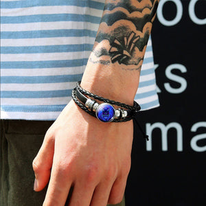 Zodiac Glow Y2K Bracelet worn on a tattooed wrist, braided black band with a blue zodiac cabochon